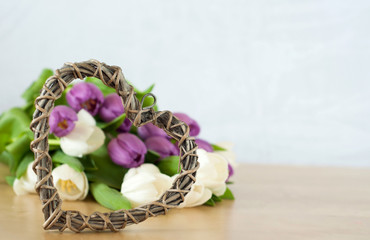 white and violet tulips on the table with heart