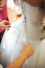beautiful bride getting ready in white wedding dress with