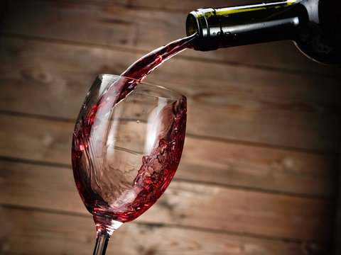 Red wine pouring on wood background