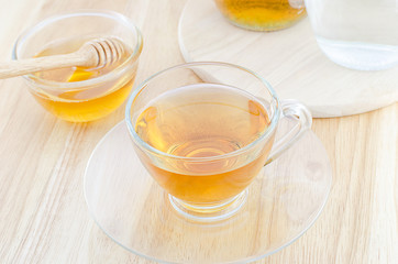 A cup of tea with honey on wooden table