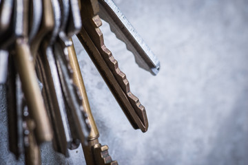 A bunch of old worn keys on the grey concrete wall