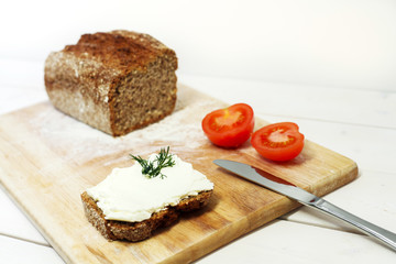 Bread lice with cream cheese and tomatoes on wood cutter 