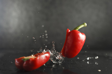 Red bell pepper dropped on wet limestone splashing water