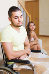 Sad girl with boyfriend in invalid chair