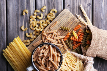 Fototapeta na wymiar Different types of pasta in containers on wooden background