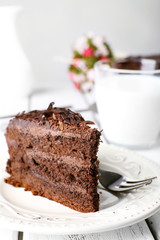 Sliced tasty chocolate cake in plate on wooden table, closeup
