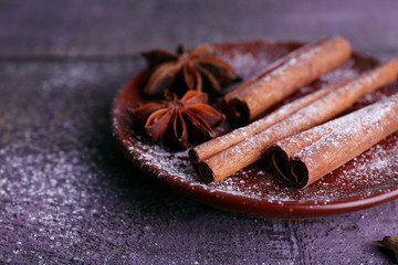 Spices in plate with powdered sugar on color wooden table background
