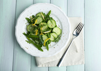 Green salad with cucumber, arugula and lemon peel on wooden table, top view