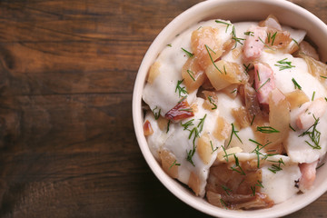 Tasty dumplings with fried onion in brown bowl, on wooden background