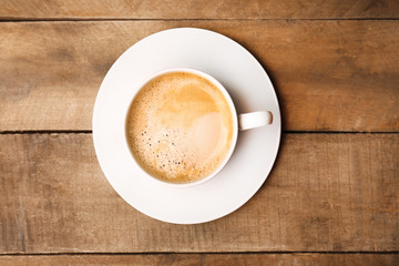 Cup of coffee on wooden table, top view