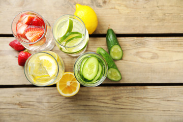 Glasses of different home made freshness healthy vitamin-fortified water on wooden table