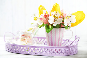 Beautiful flowers in cup, on wooden background