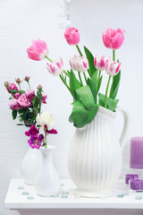 Beautiful composition with different flowers in vases on wall background