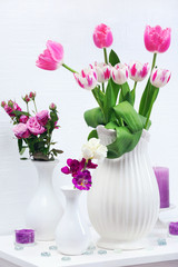 Beautiful composition with different flowers in vases on wall background