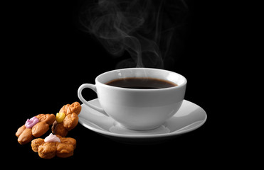 A cup of hot coffee and cookies isolated on a black background.