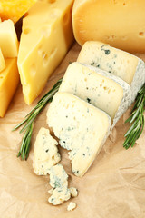 Various types of cheese with rosemary on table close up