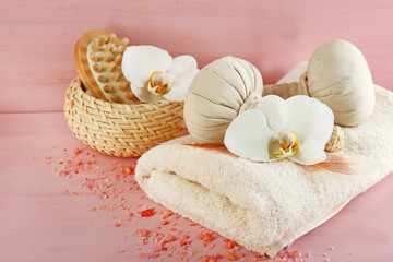 Still life with beautiful blooming orchid flower, spa treatment and pebbles, on color wooden background