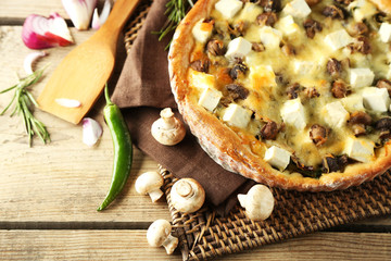 Cheese pie with mushrooms, herbs and sour creme, on wicker mat, on wooden table background