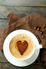 Cup of cappuccino with heart of cocoa on wooden table
