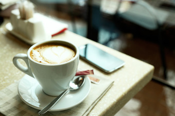 Cup of cappuccino on table in cafe