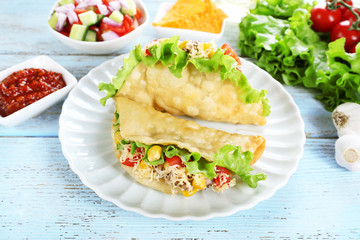 Tasty taco with tomato dip on plate and vegetables on table close up