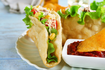 Tasty taco with tomato dip on plate on table close up
