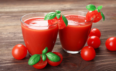 Glasses of tomato juice with vegetables on wooden background