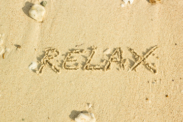 relax word handwritten on sand