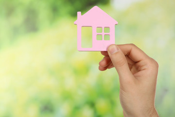 Female hand holding house on green blurred background