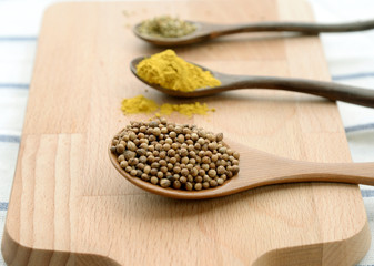 Assortment of spices in wooden spoons on wooden background