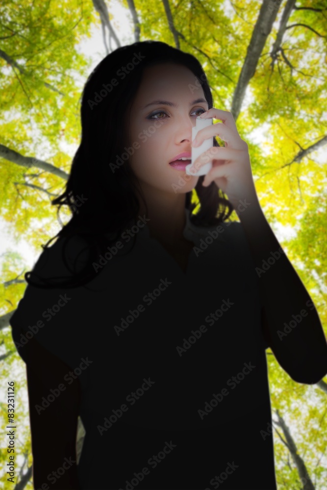 Poster Composite image of asthmatic brunette using her inhaler 