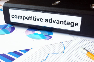 Graphs and file folder with label competitive advantage. 