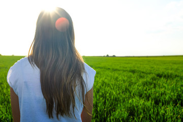 Girl is standing on a field, Photo taken from the back.