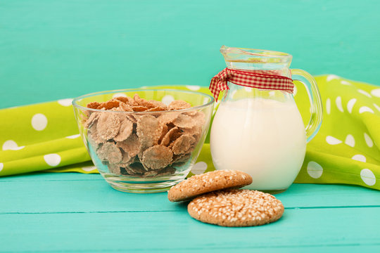 Jug of milk with muesli and cookies on blue wooden kitchen. Selective focus