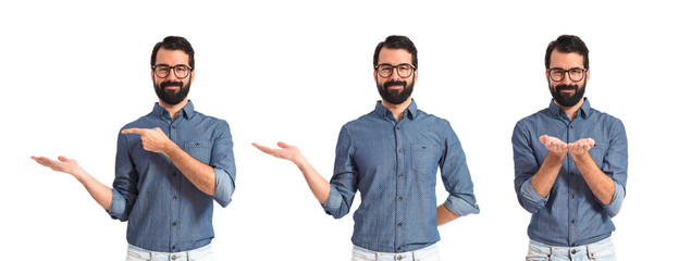 Young hipster man holding something over white background