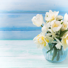 Background with fresh narcissus and tulips in blue vase