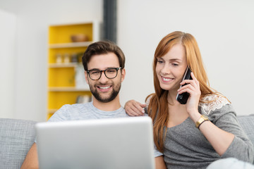 glückliches paar mit laptop und telefon zu hause