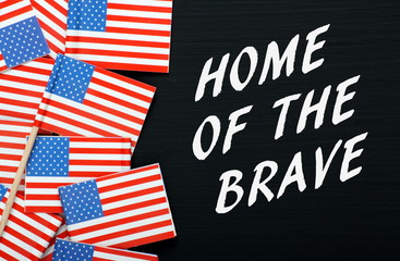 The phrase Home of the Brave with USA flags on a blackboard