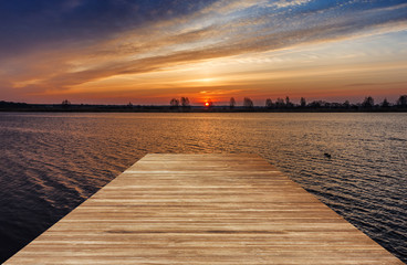 Houten pier boven een water bij zonsopgang