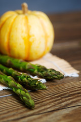 Asparagus on a mat with a pumpkin.