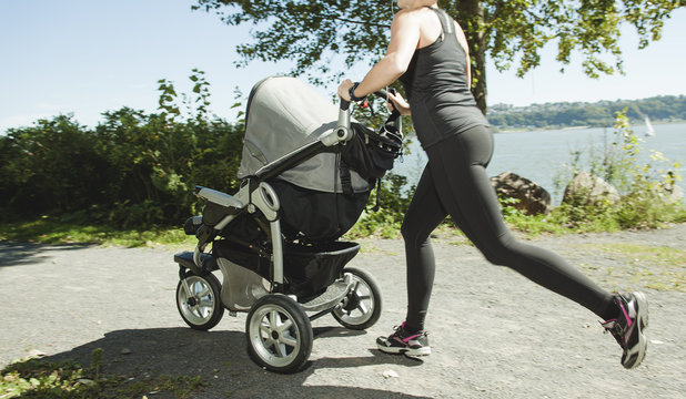 A Young mother jogging with a baby on the buggy