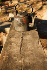 Old kettle in wooden bench outdoors