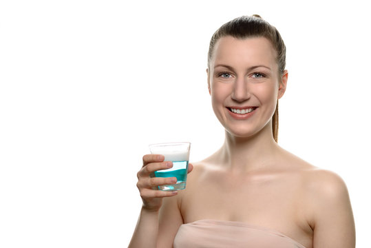 Lächelnde Frau hält ein Glas mit Mundspülung
