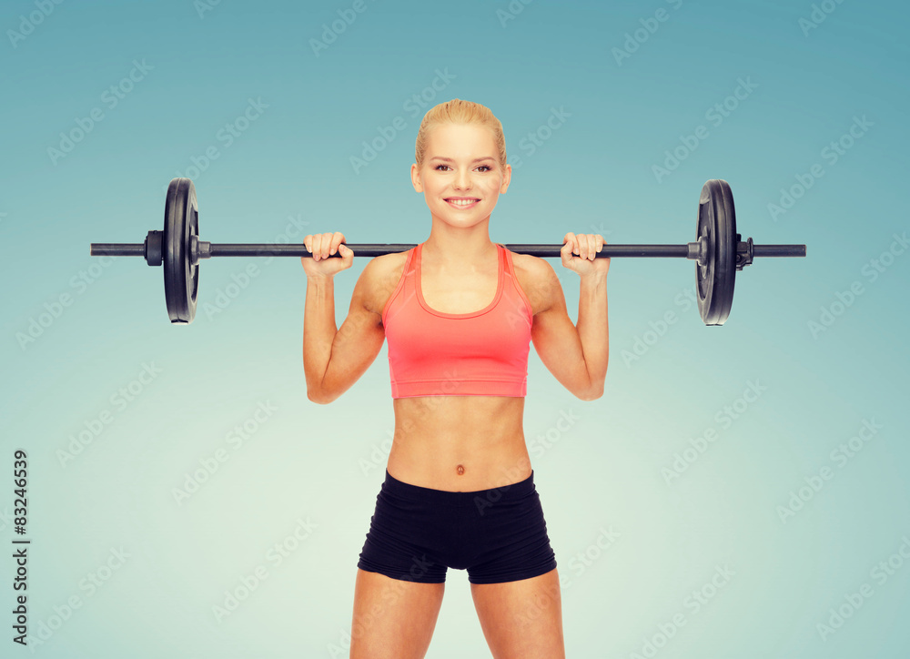 Wall mural smiling sporty woman exercising with barbell