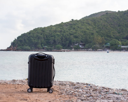 travel background with a black trolley suitcase  at a tropical b