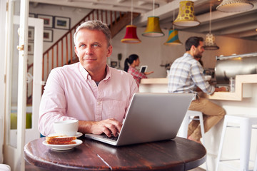 Fototapeta na wymiar Middle aged man using laptop in a cafe