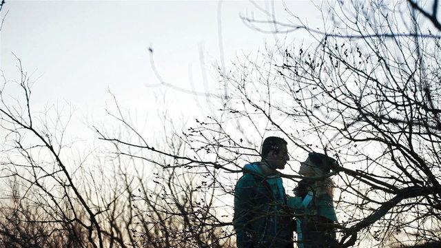 Young beautiful couple clinking glasses talking and kissing in romantic sunset surroundings of awakening spring nature