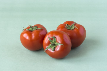 Three tomatoes on a green background