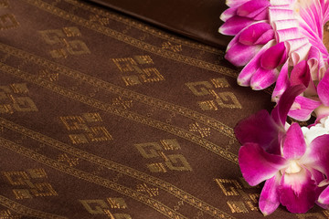 Traditional brown Thai fabric pattern with orchid garland