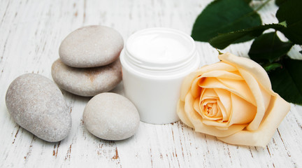 Fototapeta na wymiar cosmetic cream with spa stones and rose